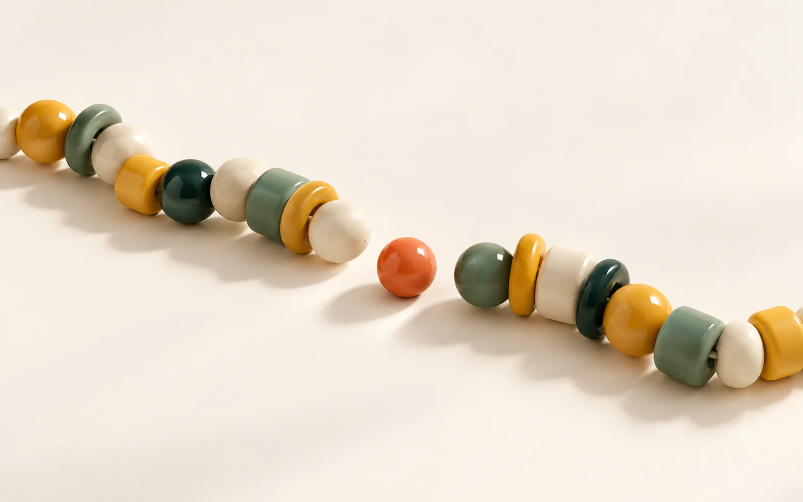Deux chaînes de perles ambre et vertes aux formes distinctes, avec une perle corail entre elles