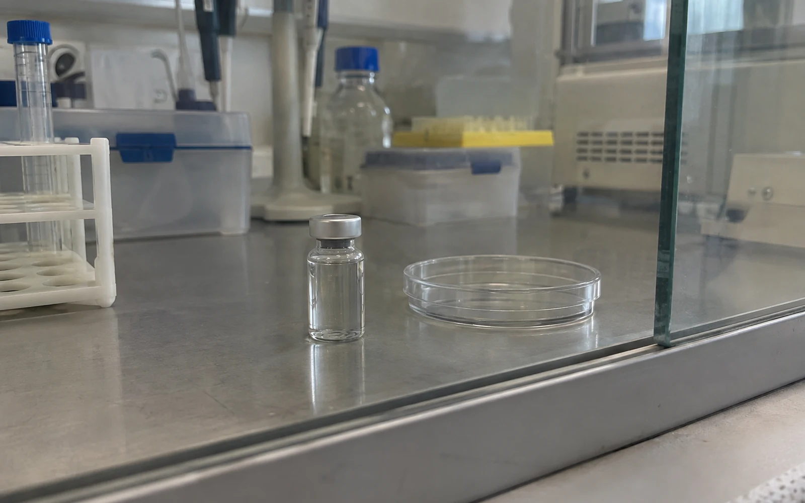 Flacon fermé sans étiquette et coupelle vide sur une paillasse de laboratoire éclairée en bleu.