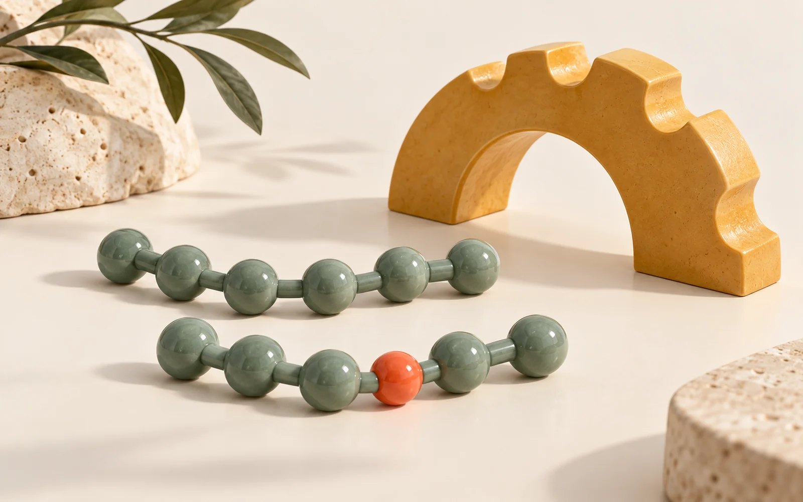 Deux chaînes de perles jade près d’une arche ambrée, avec une perle corail sur une des chaînes.